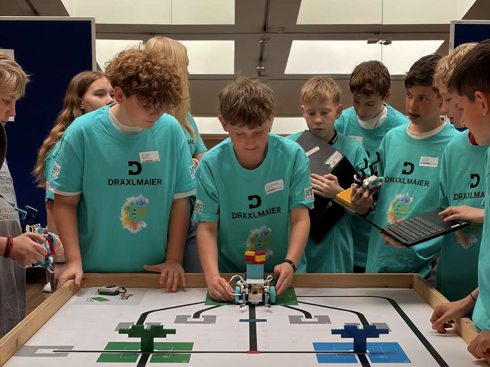 Kids working in pairs on a robot at the WRO competition field