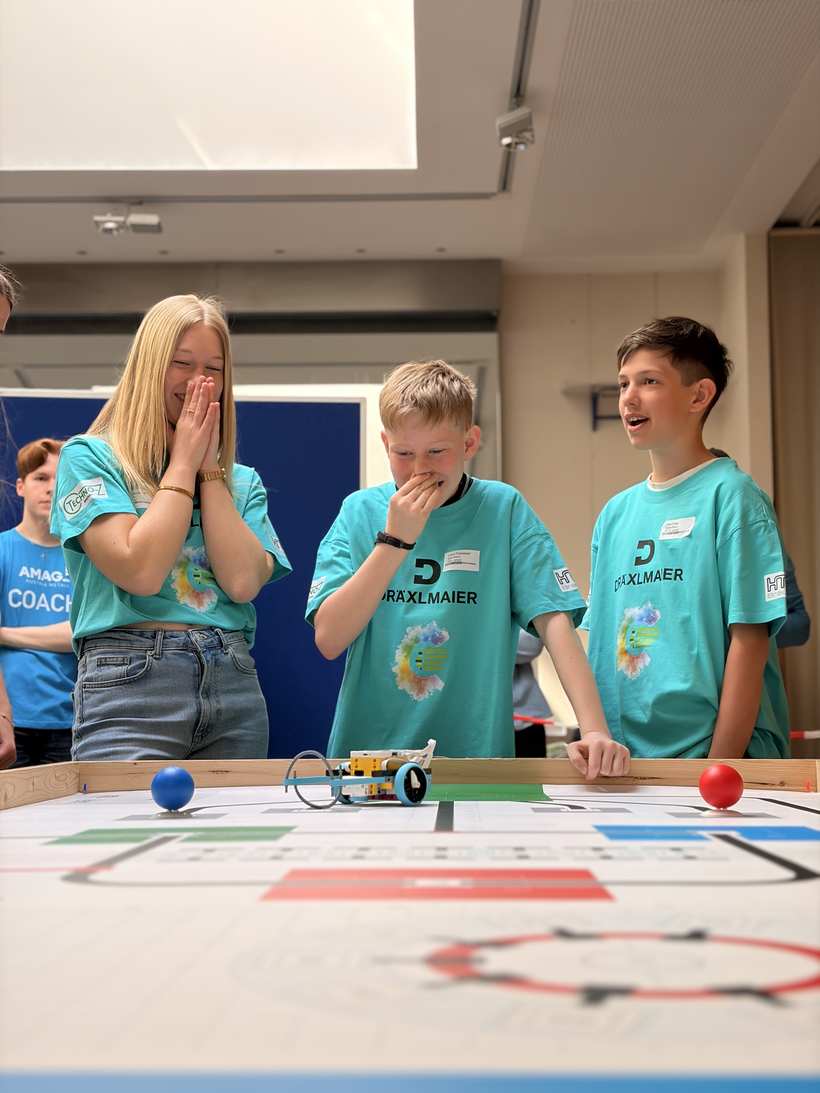 Two kids celebrating their driving robot on the WRO field